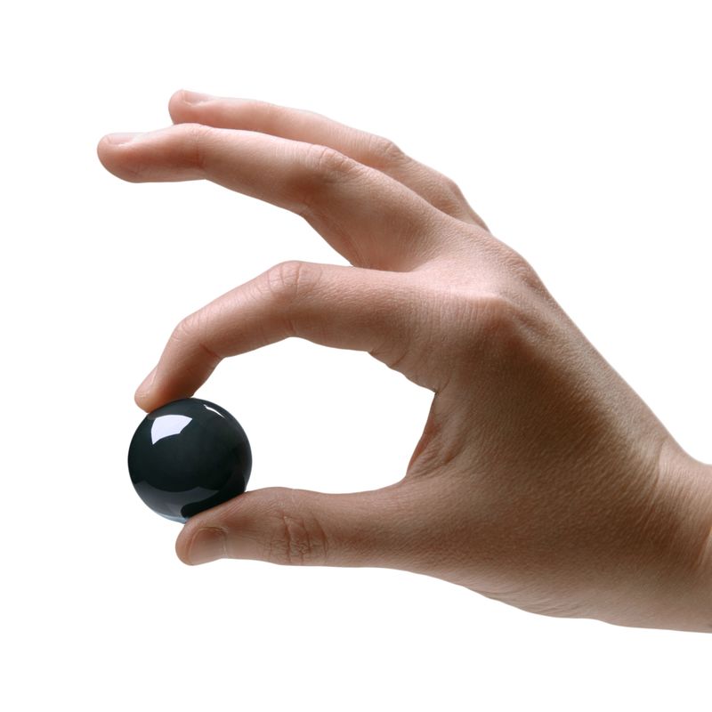 A hand holding a Jaded Glass Ben Wa Ball 30mm, showcasing its smooth black finish and sleek design.