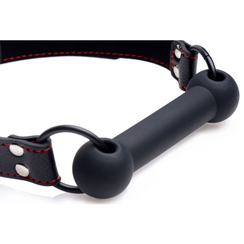 Close-up of a silicone pet bit gag with bold red stitching on a strap for playful pet sessions.