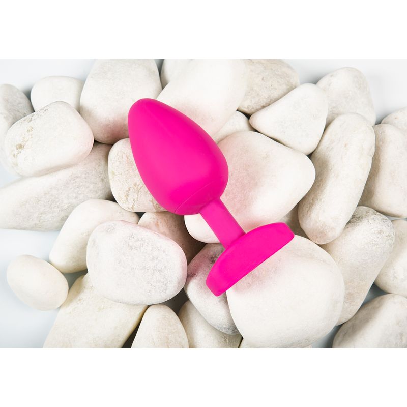 Gplug Large Bioskin Sweet Raspberry sex toy resting on white pebbles, showcasing its realistic design and vibrant color.