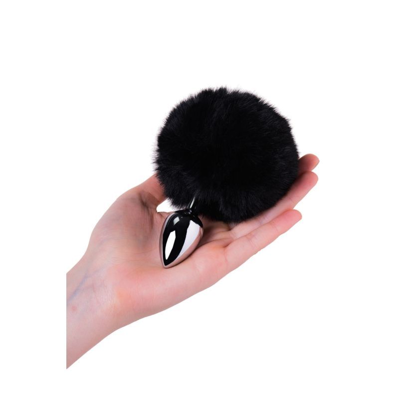 Silver anal plug with black tail held in a hand, showcasing the fluffy black faux fur and sleek metal design.
