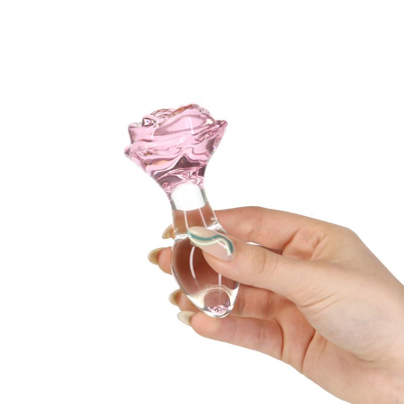 Luxurious glass anal plug in hand, featuring a beautiful pink rose base and clear gem design.