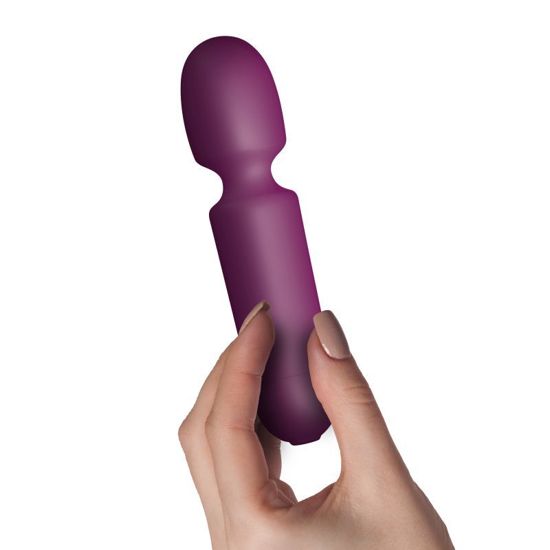 Hand holding a burgundy discreet wand vibrator made from body-safe silicone with a flexible head.