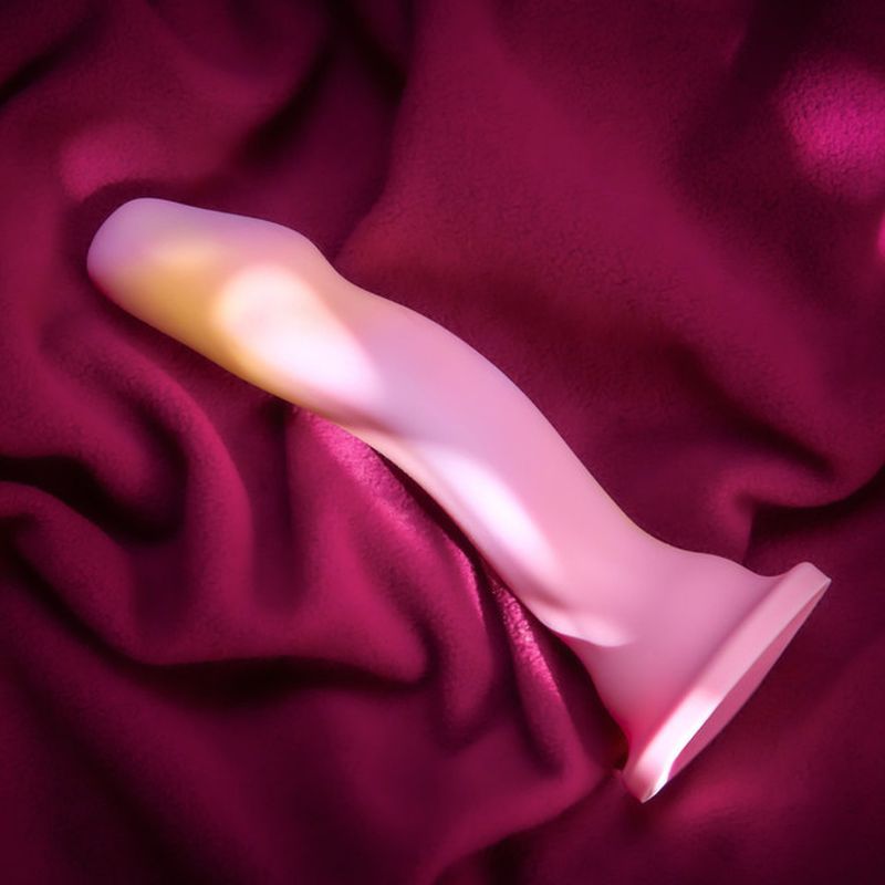 Avant Suns Out pink silicone dildo for G spot stimulation resting on soft fabric.