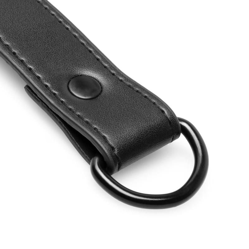 Close-up of a durable black hogtie with a metal D-ring and faux leather finish, ideal for adding excitement to your fantasies.
