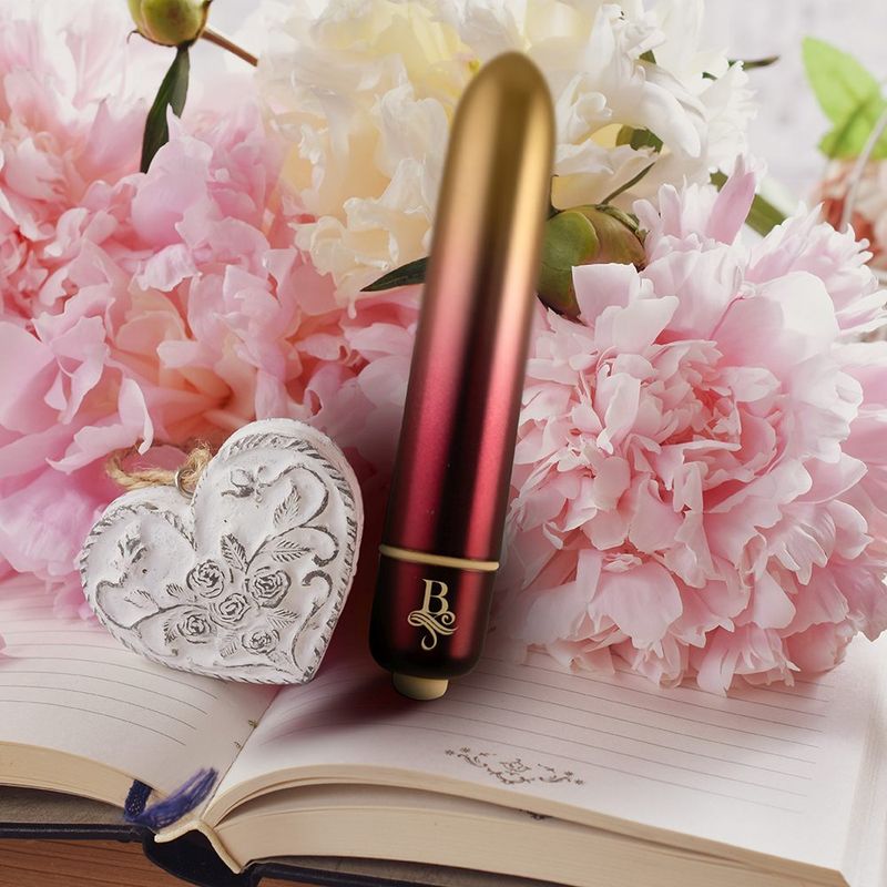 Boudoir Debutante waterproof bullet vibrator surrounded by pink flowers and a decorative heart on an open book.