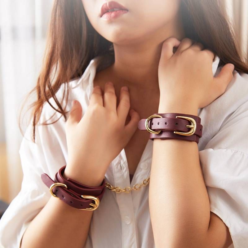 Model showcasing 8 Pc Deluxe Bondage Play Kit with burgundy leather wrist restraints and gold hardware.