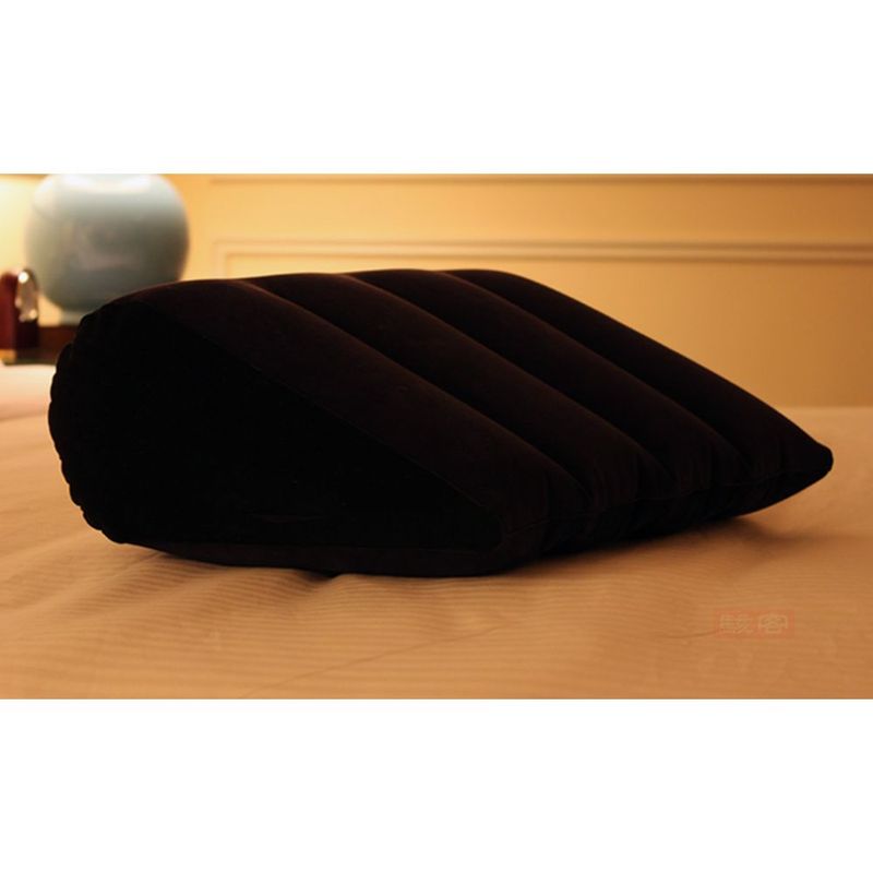 Inflatable sex positioning cushion on a bed with a soft black suede finish.
