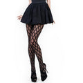 Model showcasing geo jacquard fishnet tights black paired with a black skirt and high heels for a stylish look.