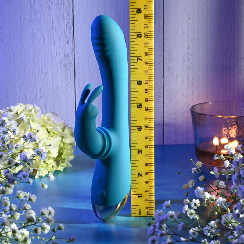 Adam & Eve SHIMMY & SHAKE VELVET RABBIT - 22.4 cm USB Rechargeable Rabbit Vibrator with flowers and ruler backdrop.