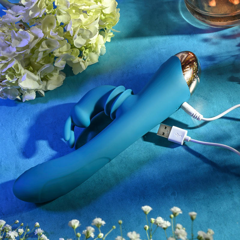 Adam & Eve SHIMMY & SHAKE VELVET RABBIT - 22.4 cm USB Rechargeable Rabbit Vibrator on a blue background with flowers.