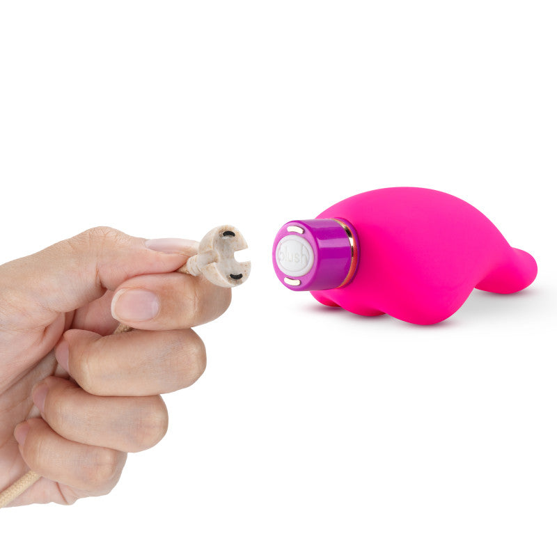 A hand holding a charging cable next to the Aria Epic AF - Fuschia USB Rechargeable Stimulator.