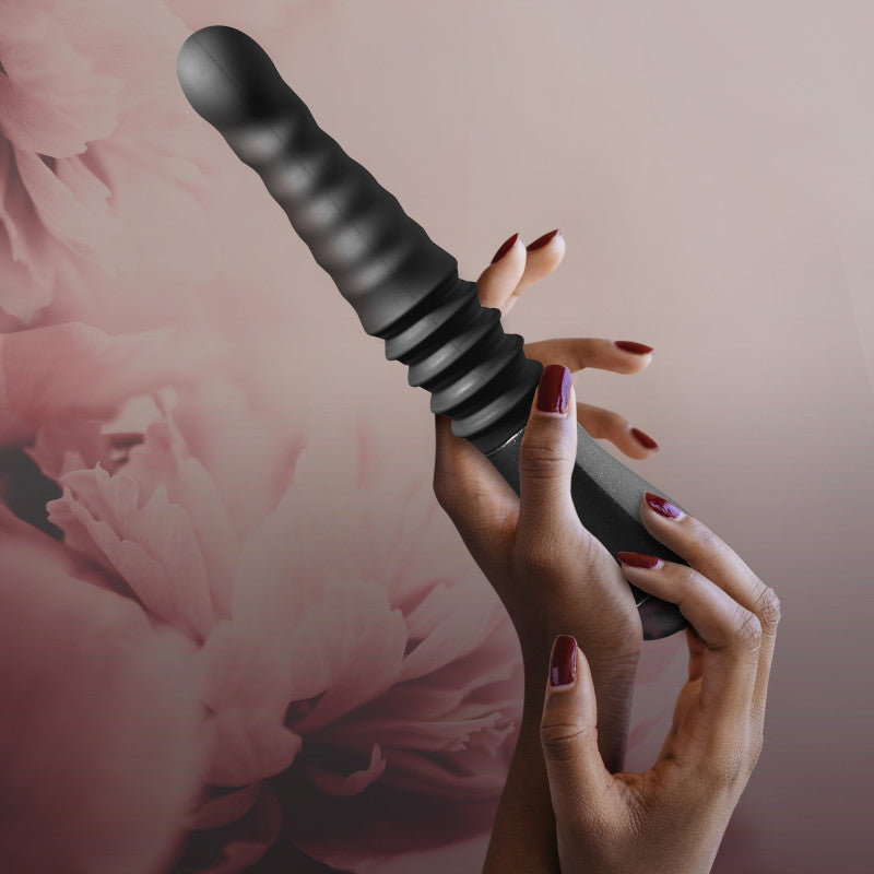 Temptasia Lazarus thrusting dildo for G spot stimulation held in hand, featuring ribbed body and ergonomic handle.