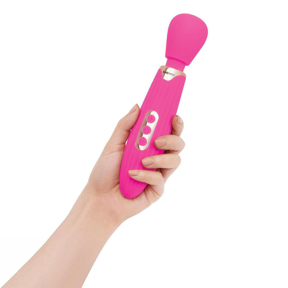 Hand holding the Bodywand RUMBLE WAND, a pink rechargeable massage wand with multiple vibration modes.