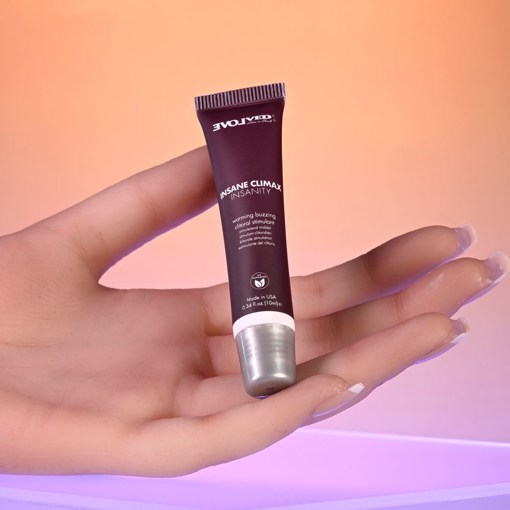 Evolved INSANE CLIMAX - INSANITY - Warming Buzzing Clitoral Stimulation Gel - 10 ml in a hand with a glowing background.