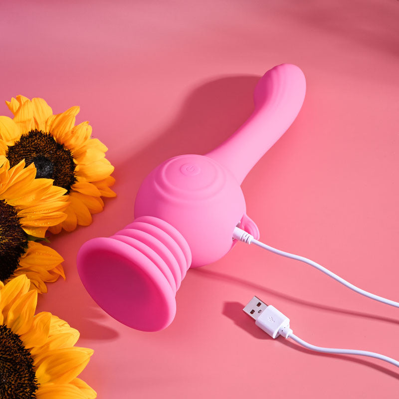 Evolved GYRO VIBE - 24.8 cm USB Rechargeable Super Vibrator beside sunflowers, showcasing its vibrant pink color.