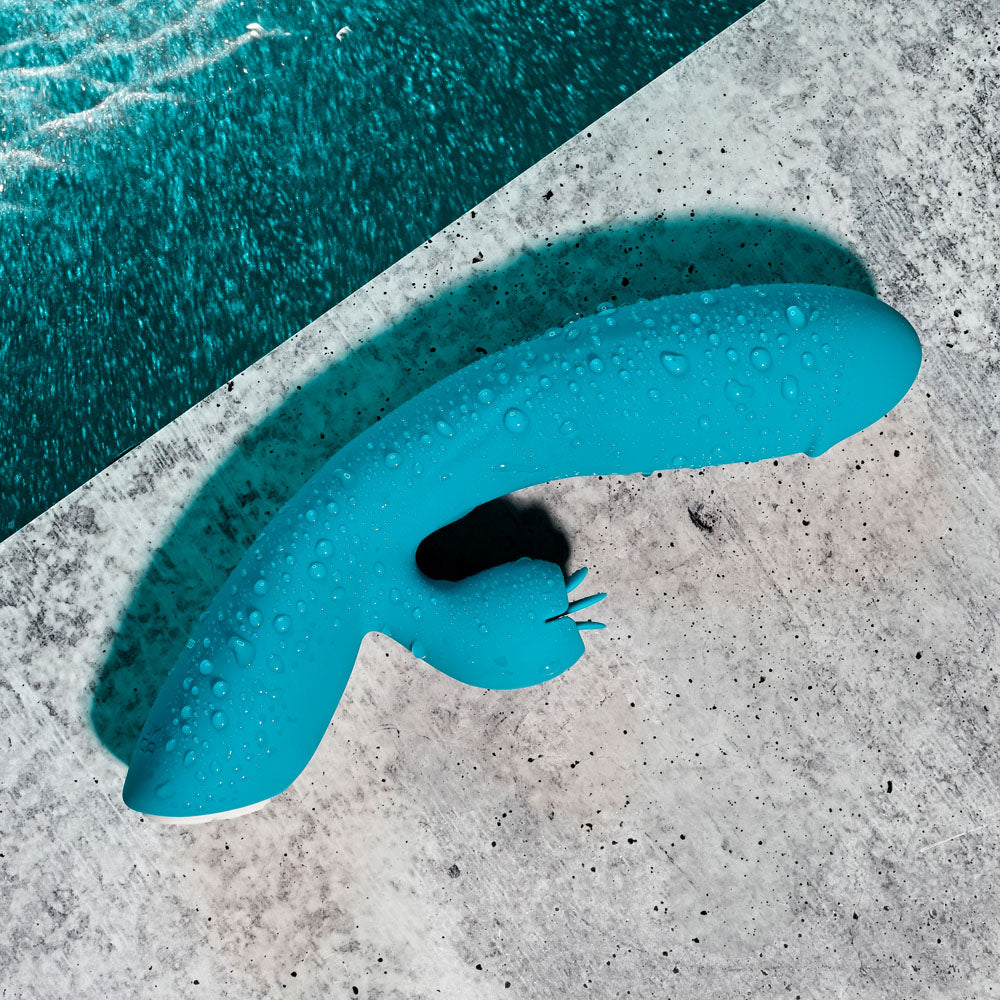 USB rechargeable rabbit vibrator on a concrete surface, showcasing its sleek design and water-resistant features.