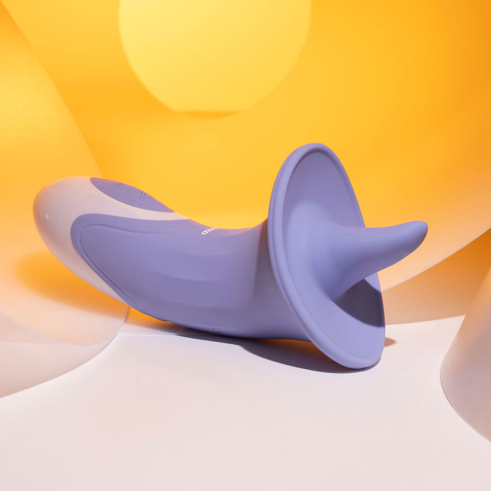 Evolved LIX & KISSES USB rechargeable tongue stimulator in a soft purple design on a vibrant background.
