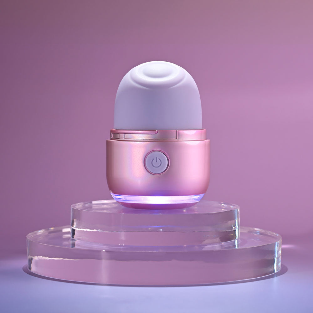 Evolved VACATION VIBES USB rechargeable tapping stimulator on a glass display with pink lighting.