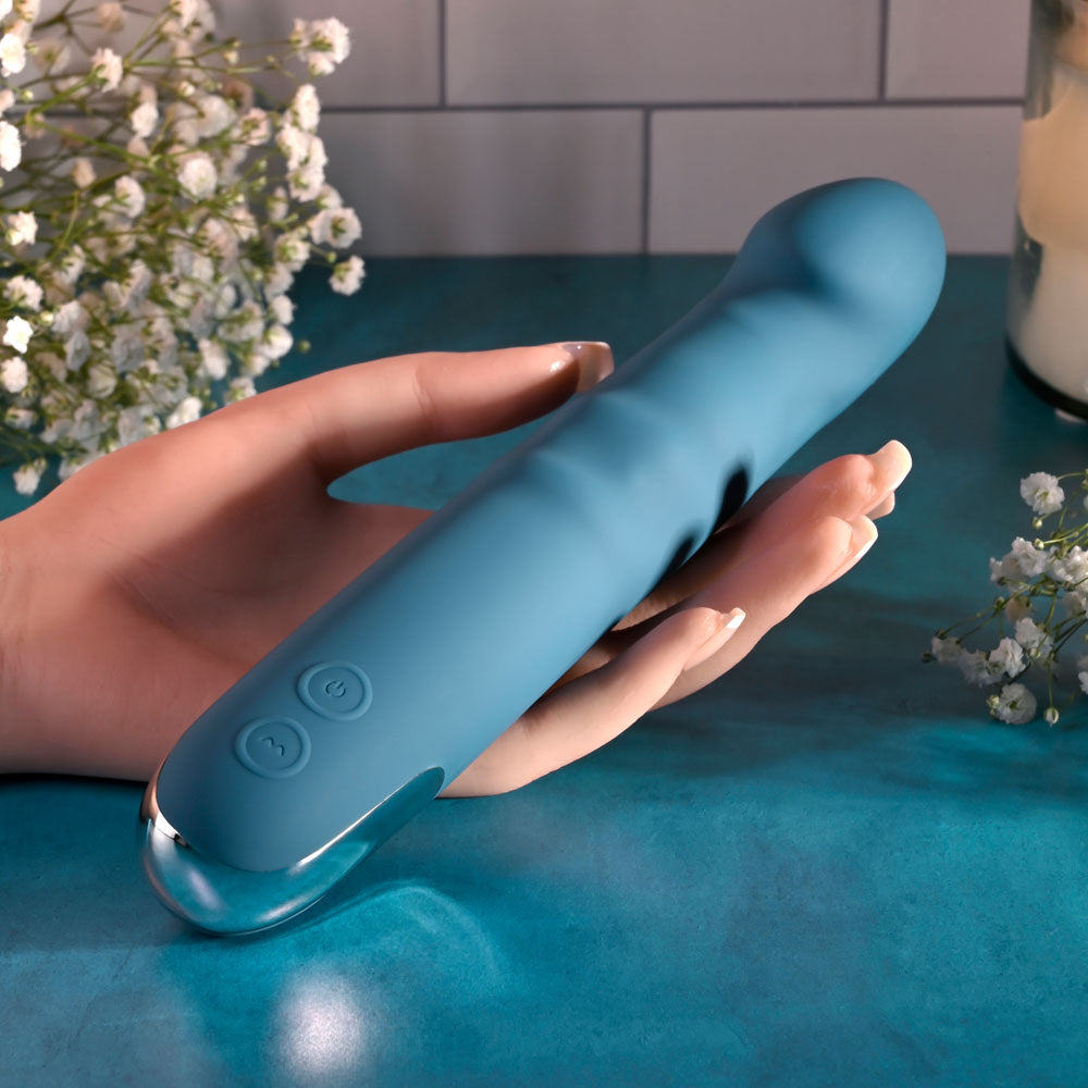 Evolved QUEEN OF ALL TRADES - 22.6 cm USB Rechargeable Thrusting & Rotating Vibrator held in a hand with decorative flowers.