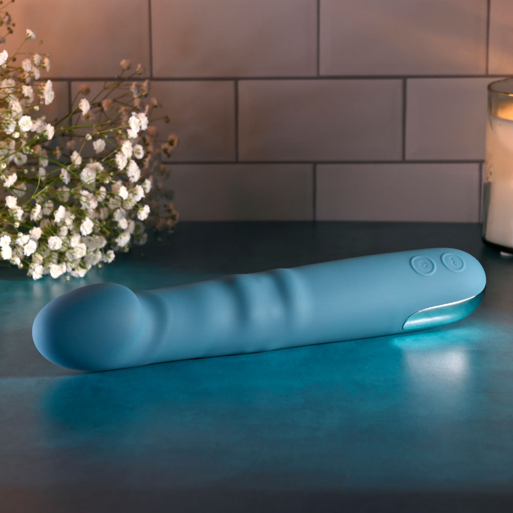 Evolved QUEEN OF ALL TRADES - 22.6 cm USB Rechargeable Thrusting & Rotating Vibrator displayed with soft lighting and flowers.