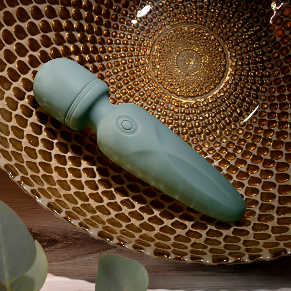 Evolved RUMBLE WAND - Olive  13.4 USB Rechargeable Mini Massage Wand positioned in an artistic bowl.