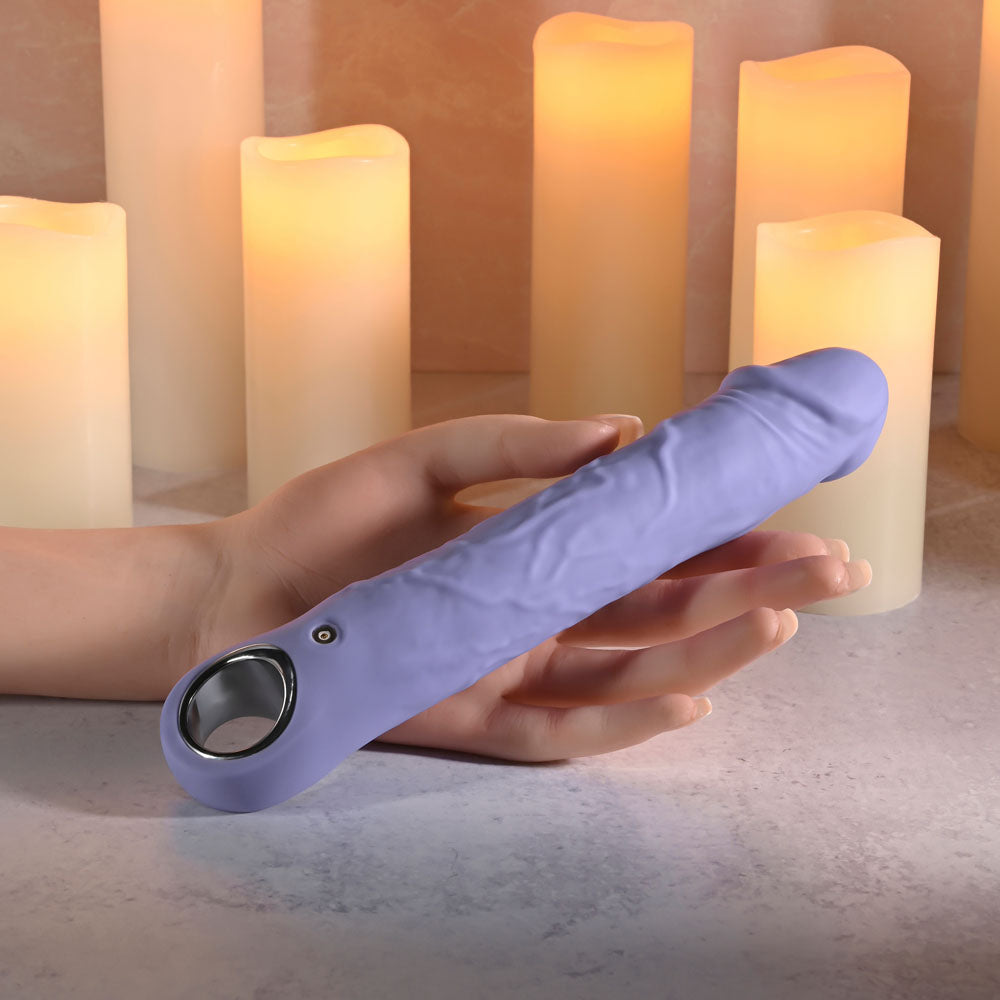 Evolved LARGE FANTASY - 21.8 cm USB Rechargeable Vibrator in a hand, set against softly glowing candles.