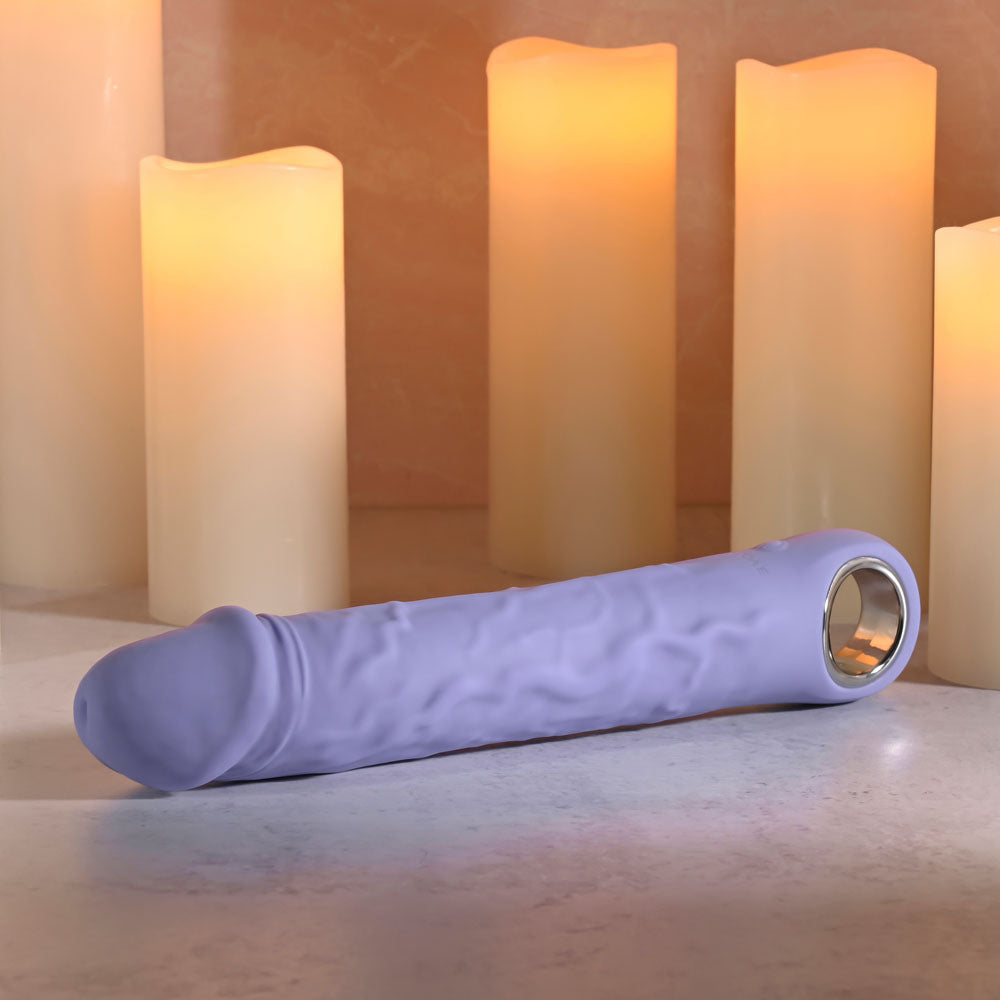 Evolved LARGE FANTASY - 21.8 cm USB Rechargeable Vibrator on a surface with illuminated candles in the background.