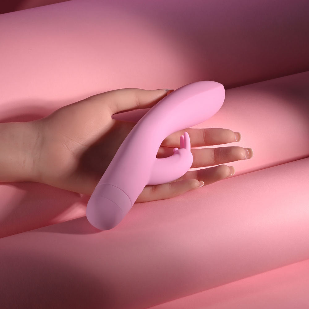 Evolved CUSHY BUNNY - 19.1 cm USB Rechargeable Rabbit Vibrator held in hand on pink background.