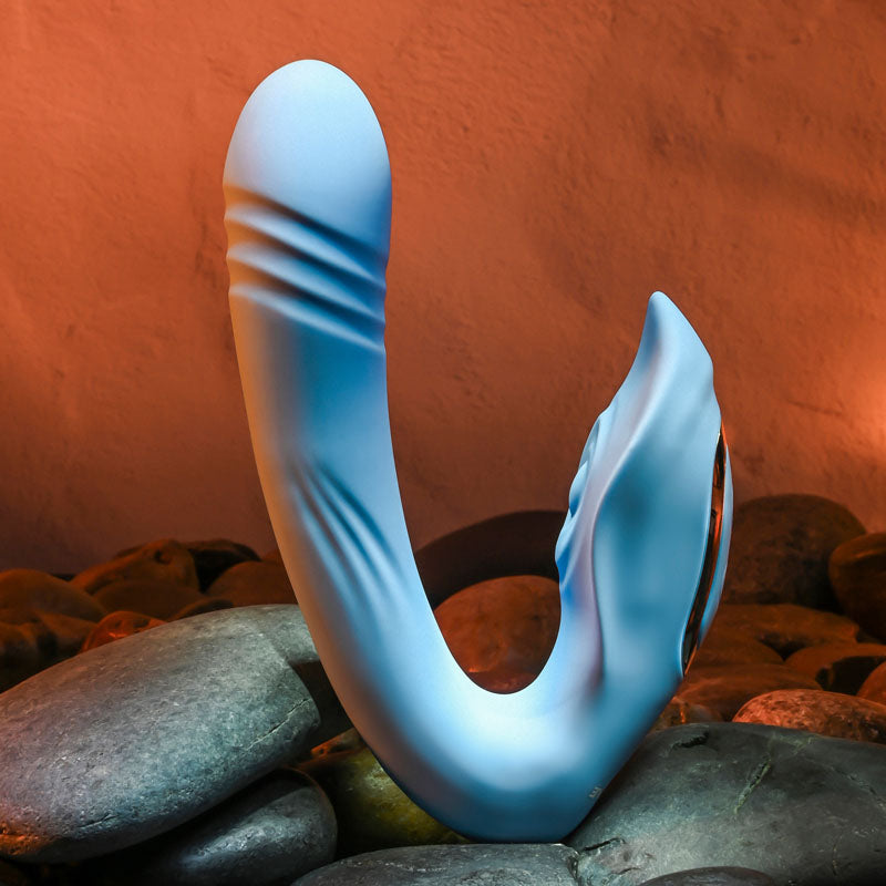 Evolved TAP & THRUST - USB Rechargeable Dual Vibrator showcasing a curved design on textured stones.
