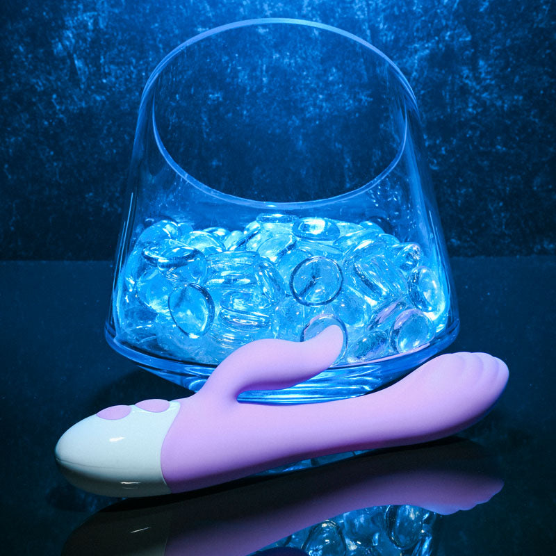 Evolved PLEASING PETAL - Lilac 19.7 cm USB Rechargeable Rabbit Vibrator next to a bowl of ice cubes.