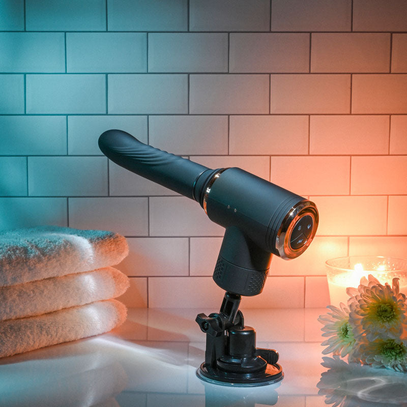 Evolved TOO HOT TO HANDLE - USB Rechargeable Thrusting Vibe with Stand on a countertop beside towels and a candle.