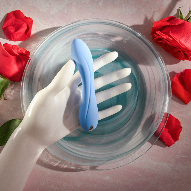 Evolved  CRUSH - 12 cm USB Rechargeable Mini Vibrator resting in a hand above water with rose petals.