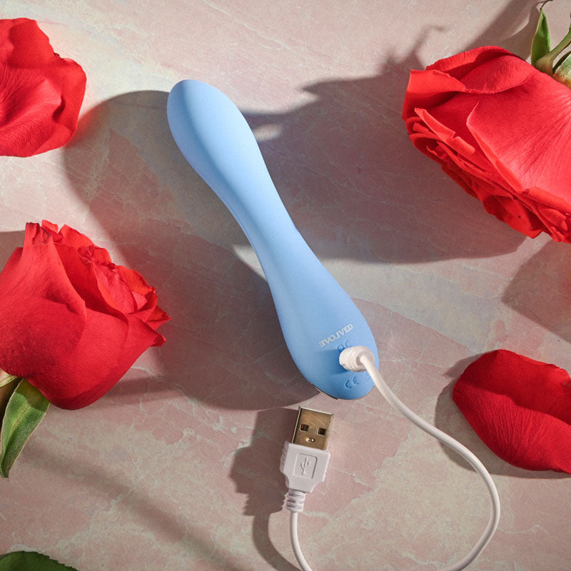Evolved  CRUSH -  12 cm USB Rechargeable Mini Vibrator surrounded by red roses, showcasing its smooth design and charging cable.