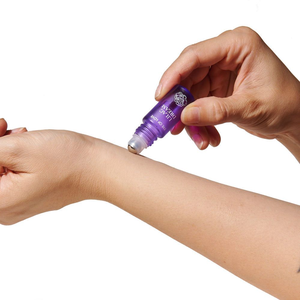 Woman applying Eye Of Love Love In Bloom Pheromone Perfume Roll-On Set - Day to Night (Sunny Daze & Lilac Dream) Pheromone Perfume Oils for Women to attract Men - 10 ml Roll On Bottles on wrist.