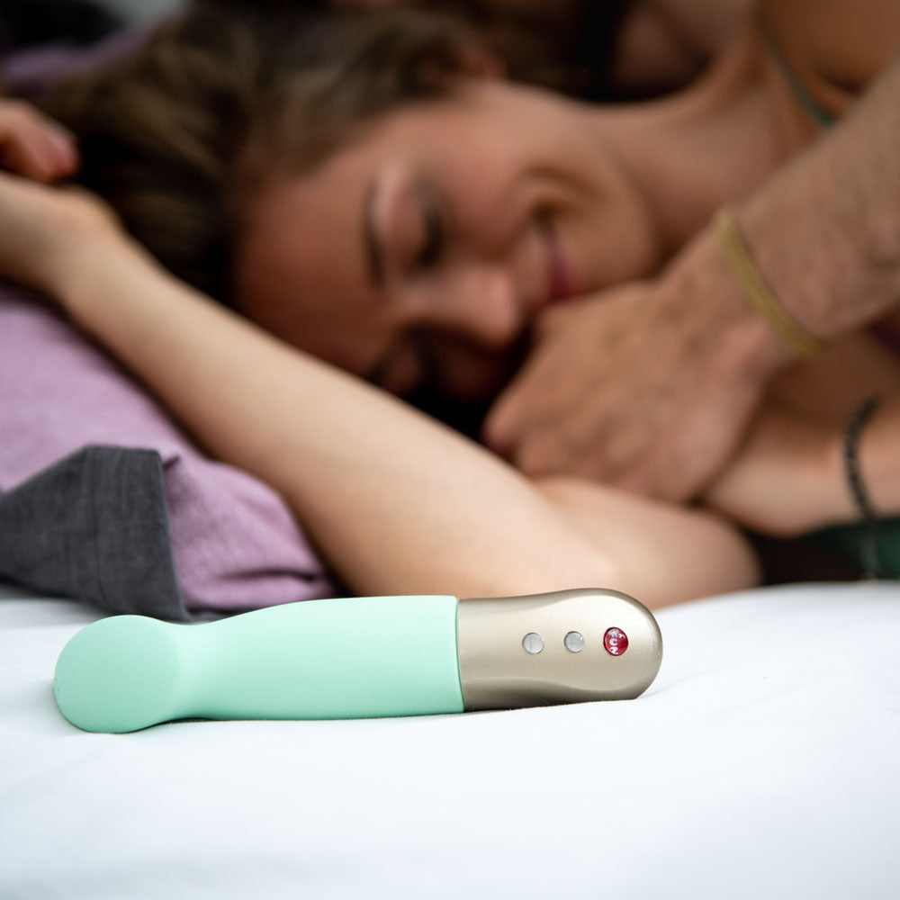 Fun Factory SUNDAZE pistachio - Pistachio 17.5 cm USB Rechargeable Thrusting Vibrator on a bed with a couple.