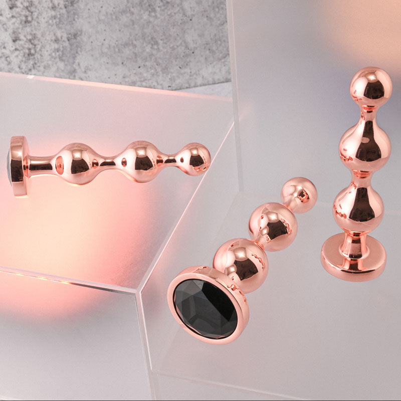 Gender X GOLD DIGGER SET -  Metallic Butt Plugs - Set of 3 Sizes displayed on a stylish surface.