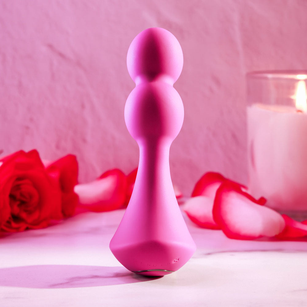 Gender X BALL GAME -  13.5 cm USB Rechargeable Vibrating Butt Plug in pink with roses and candle in background.