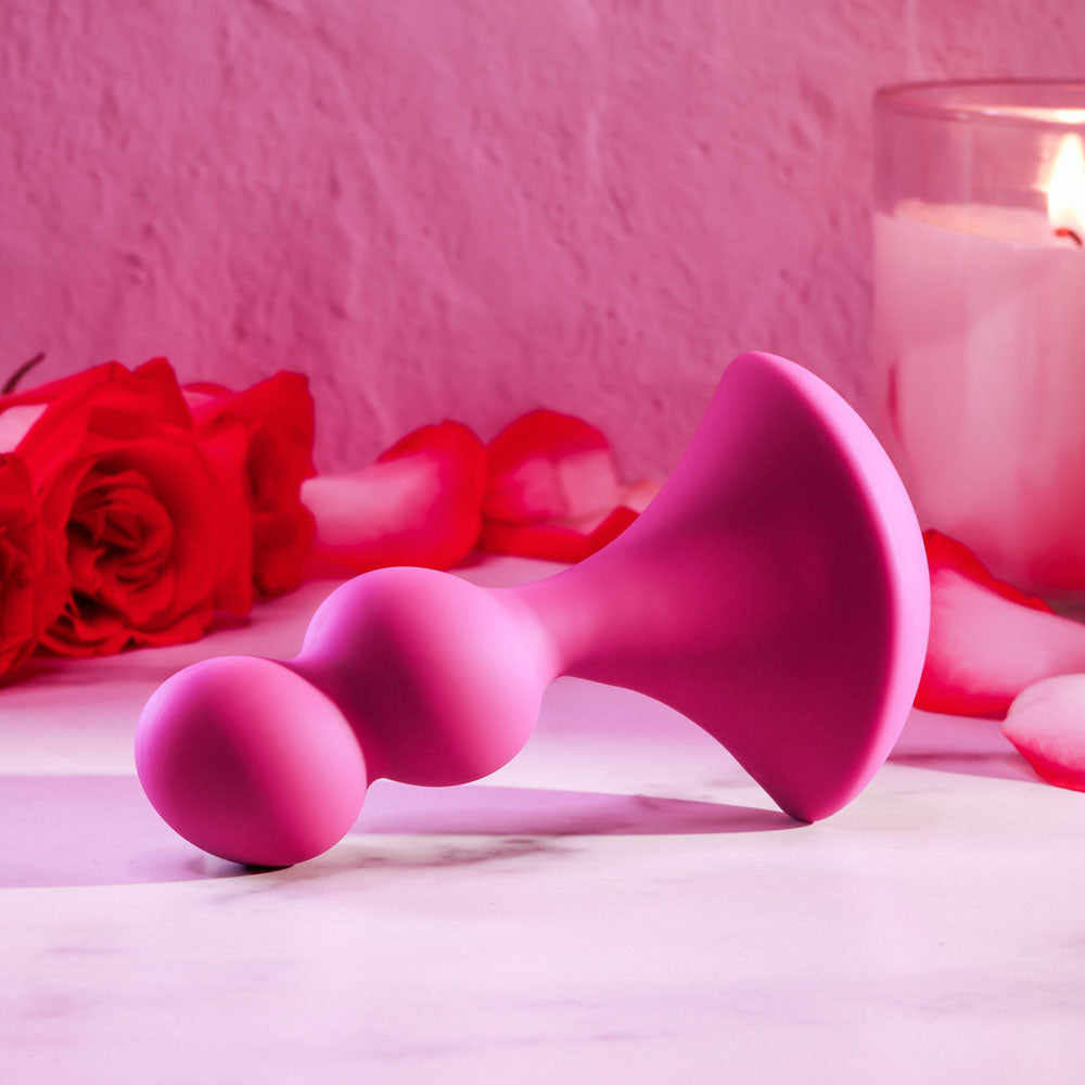 Gender X BALL GAME -  13.5 cm USB Rechargeable Vibrating Butt Plug in pink silicone with roses in the background.