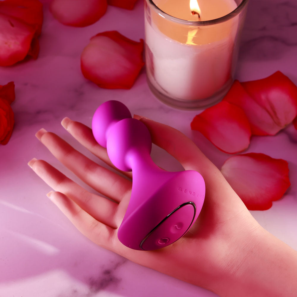 Gender X BALL GAME -  13.5 cm USB Rechargeable Vibrating Butt Plug on a hand amidst rose petals and candlelight.