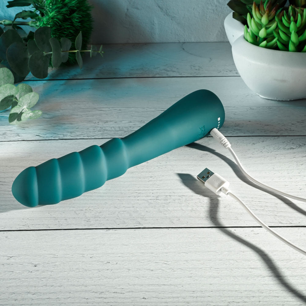 Gender X SCORPION - 21.2 cm USB Rechargeable Vibrator charging with USB cable on a wooden surface.