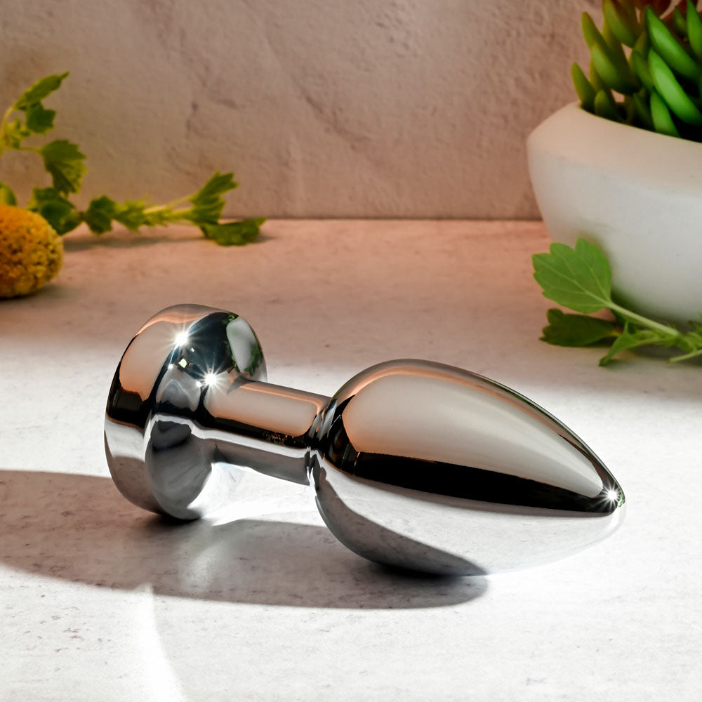 Gender X ROCKIN METAL PLUG XL - 10.5 cm USB Rechargeable Vibrating XL Butt Plug on a countertop with plants.