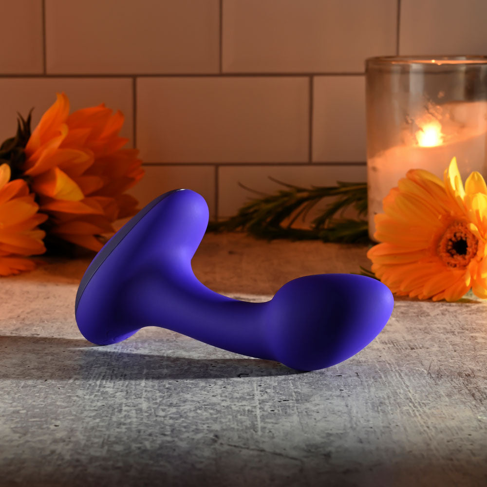 Gender X ANYBODYS PLUG -  11.4 cm USB Rechargeable Vibrating Butt Plug on a table surrounded by flowers.