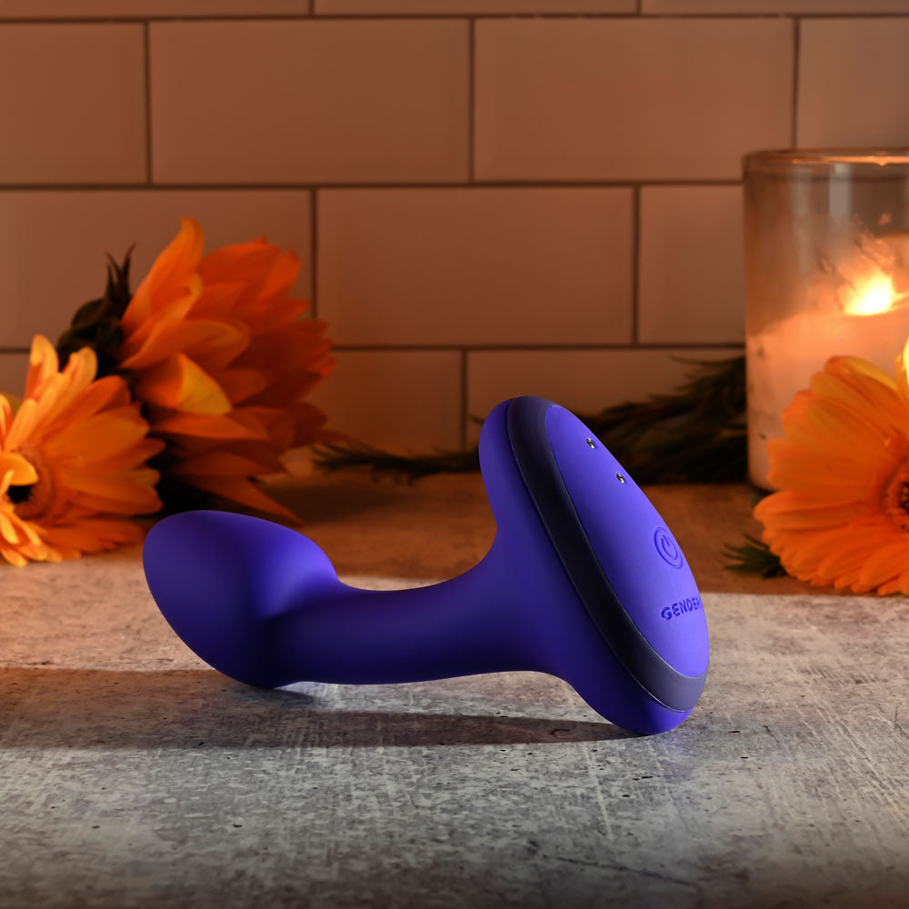 Gender X ANYBODYS PLUG - 11.4 cm USB Rechargeable Vibrating Butt Plug on a surface surrounded by flowers and candles.