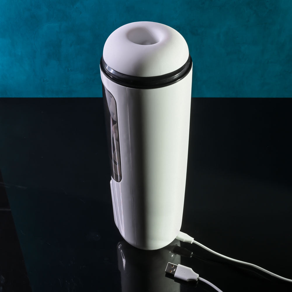 Gender X GET YOUR STROKE ON - USB Rechargeable Thrusting & Vibrating Auto Masturbator on a dark surface with USB cable.