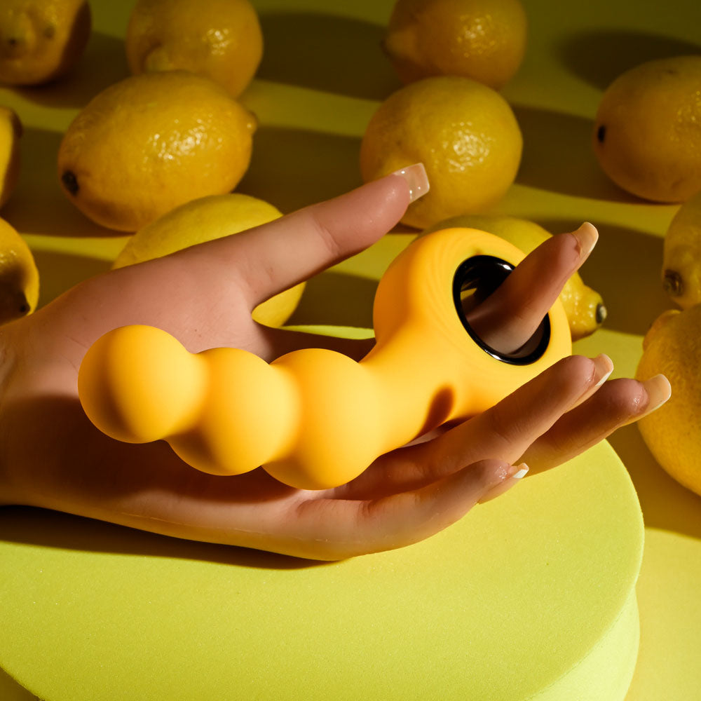 Gender X BUMBLE -  14.9 cm USB Rechargeable Butt Plug displayed on hand with lemons in background.