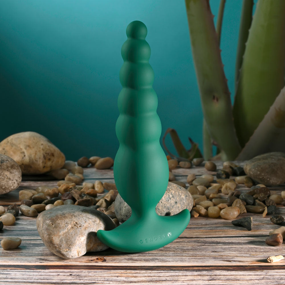Gender X THE RATTLER - 17 cm USB rechargeable vibrating anal plug among rocks and greenery.