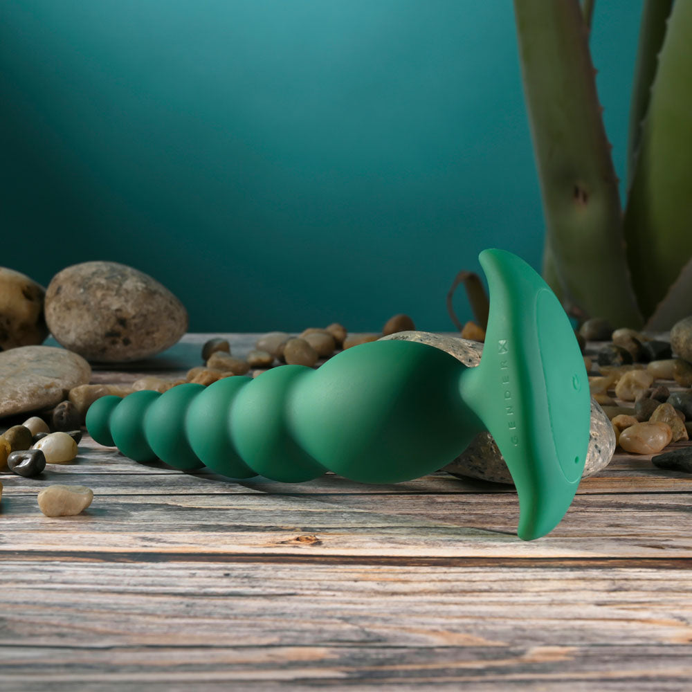 Gender X THE RATTLER -  17 cm USB Rechargeable Vibrating and Twirling Anal Plug on a wooden surface.