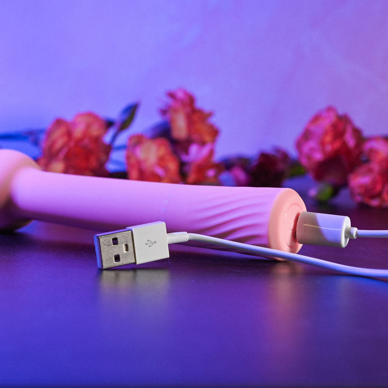 Gender X FLEXI WAND - 16.6 cm USB Rechargeable Vibrator charging with flowers in the background