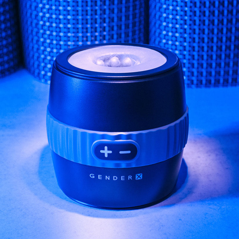 Gender X BARREL OF FUN -  USB Rechargeable Stroker illuminated with blue lighting on a table.