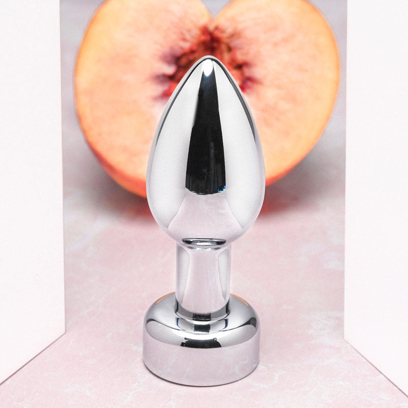 Gender X ROCKIN' METAL PLUG - Metallic 9.3 cm USB Rechargeable Butt Plug against a peach background.